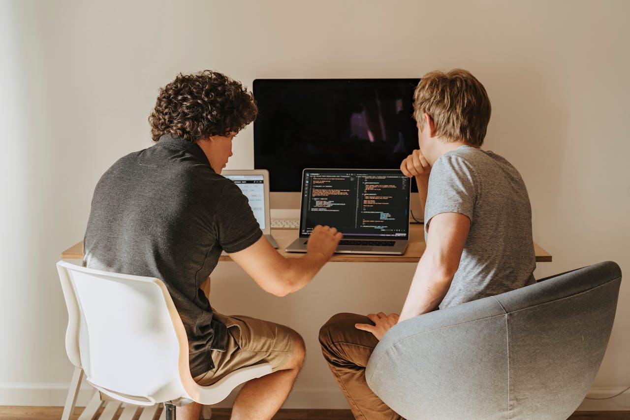 Dos personas, hombres, escribiendo código para hacer un sitio web trabajando